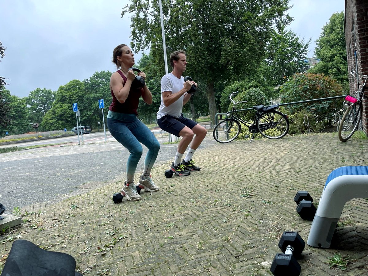 Een man en een vrouw doen tegelijk een kniebuiging met gewicht