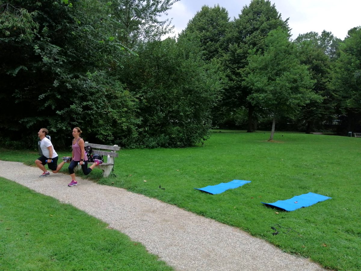 Twee mensen trainen samen bij een bankje in een park