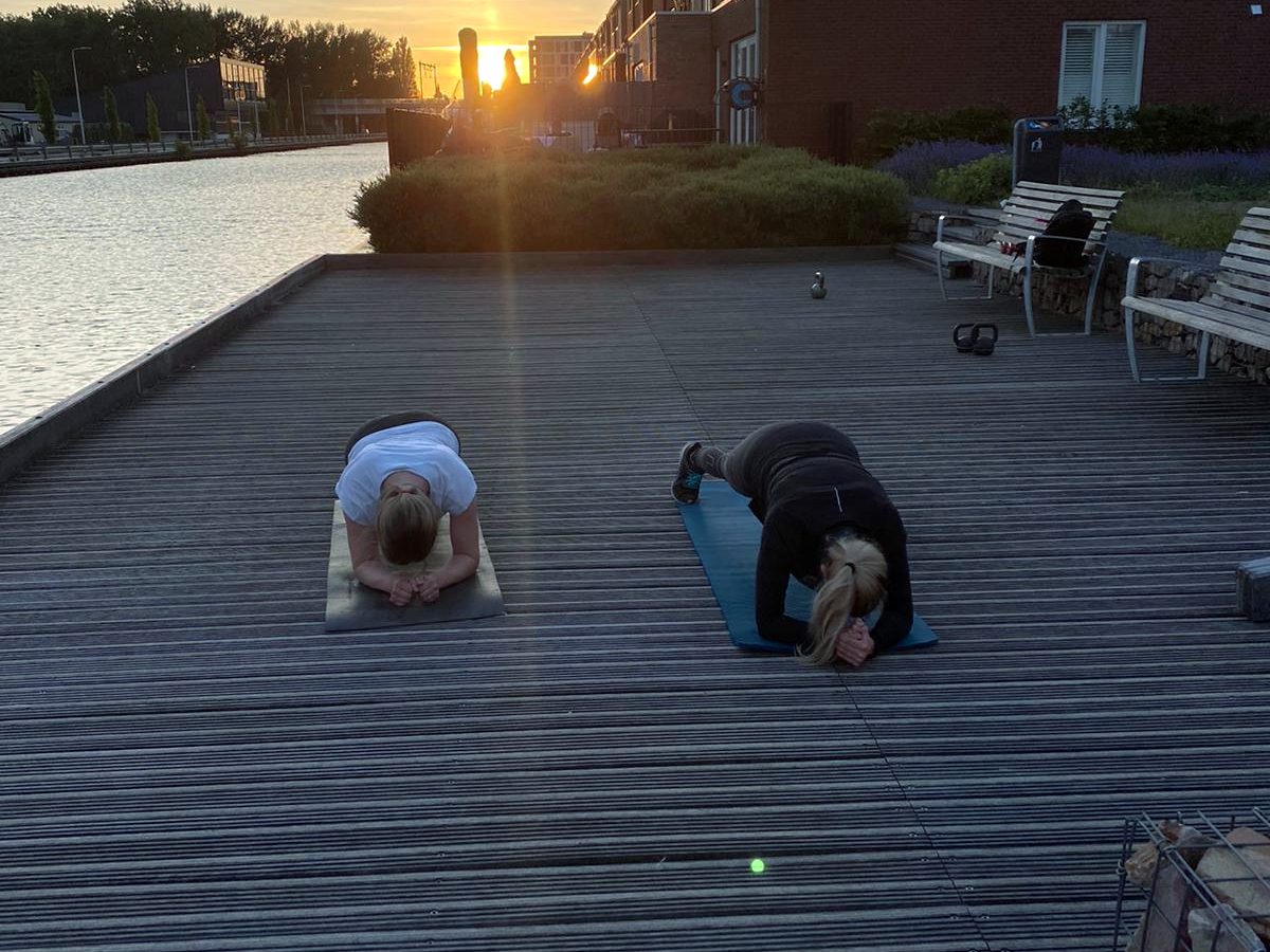 Twee mensen trainen op een vlonder bij zonsopgang